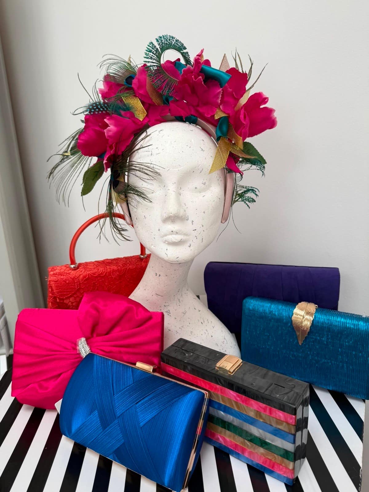 Fuchsia flower crown with peacock feathers and teal bows, with brightly coloured occasion clutches