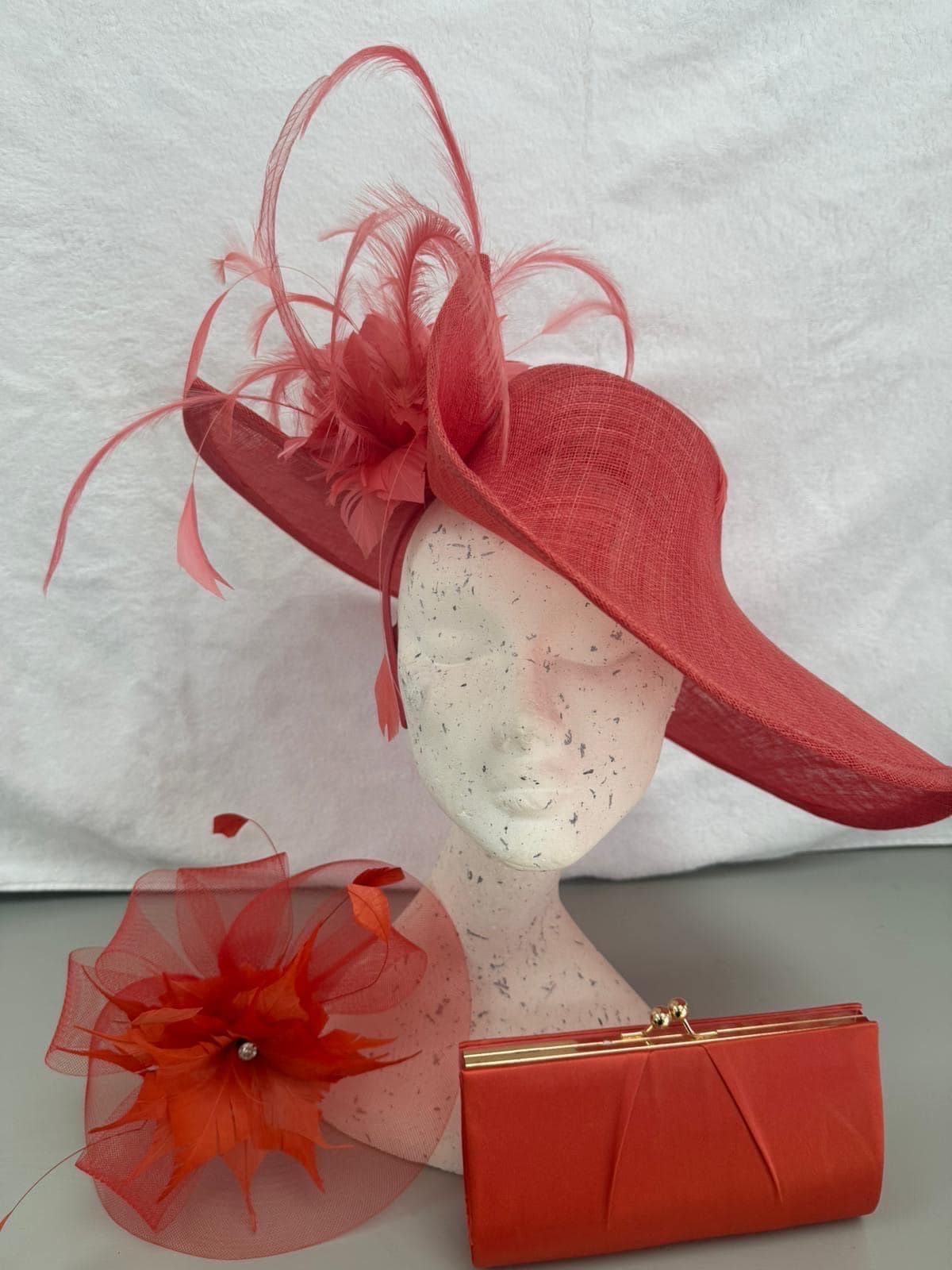 Coral wide-brim hat with curled feathers, coral flower fascinator and satin clutch
