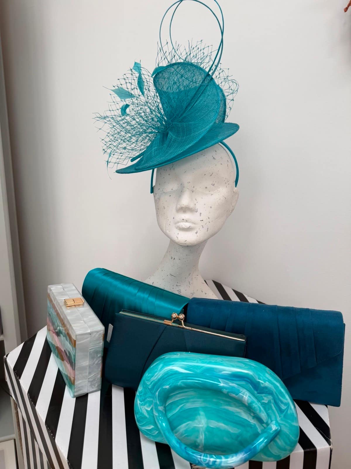 Teal twist hatinator with birdcage netting and quills, with teal and navy clutch bags